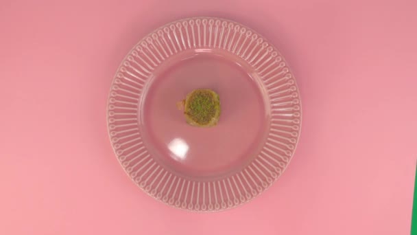 Time lapse video. A woman lays out oriental sweets on a plate. Pink plate with dessert on a pink table. Baklava. Gender party. — Stock Video