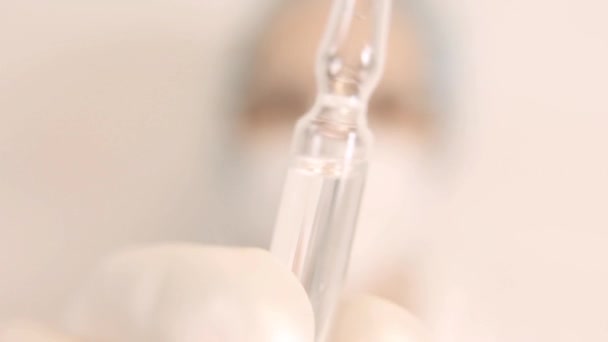 Extreme Κοντινό πλάνο ενός επιστήμονα, νοσοκόμου ή γιατρού με λευκό αναπνευστήρα, γάντια και προστατευτικά γυαλιά, ο δημιουργός του εμβολίου του κορωναϊού κρατά μια λευκή διαφανή φύσιγγα. Ο γιατρός κοιτάζει — Αρχείο Βίντεο