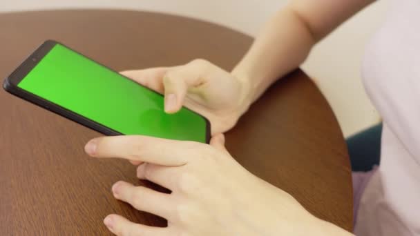 4ks.sideビュー。緑の画面で黒いスマートフォンを使用している女性写真をスクロールしたり、指を押したり、ソーシャルメディアのインターネットを読んだり、テキストを入力したり、オンラインで買い物をしたりする人の手。２つの携帯電話 — ストック動画