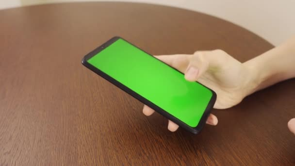 4k.Sides view. Woman using black smartphone with green screen.Hands of person scrolling up photos, pressing finger, reading social media internet, typing text or shopping online. Mobile phone in two — Stock Video