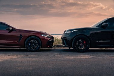 Yepyeni BMW M8 yarışması ve Range Rover Velar SVAutobiography Dynamic günbatımında. Nikolaev, Ukrayna - Ağustos 2021.