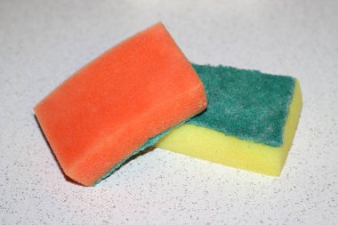 Bulaşık yıkamak için iki eski sünger, sarı ve turuncu, yeşil kenarlı, açık arkaplan.