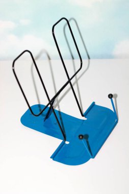 Ders kitapları için okul desteği, demirden yapılmış, siyah ve mavi, açık arkaplanda.