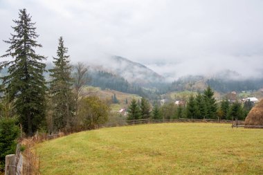 Misty morning in the Carpathian mountains in autumn. White fog over the dreamy mountain range, covered with green forest