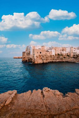Polignano a Mare, İtalya - Ağustos 2021: Bari ilindeki Polignano a Mare panoramik terasından, gökyüzü beyaz bulutlu, dikey
