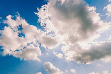 Mavi gökyüzü, beyaz bulutların arkasında güneş