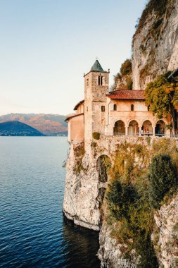Leggiuno, Varese, İtalya - Aralık 2021: Santa Caterina del Sasso Hermitage, Maggiore Gölü üzerinde gün batımında