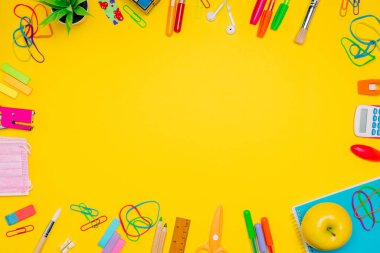 Milan, İtalya - Ocak 2022: Sarı arkaplan, renkli kalemler, etiketler, ataçlar, hesap makinesi, şablonlar ve daha fazlası üzerinde sıralanmış kırtasiye ürünleri serileri, okul konseptine geri dönüş, düz konsept, boş alan