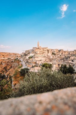 Matera, İtalya - Ağustos 2021: Belvedere Colombo 'dan Sassi di Matera' nın geniş görüşü (Sant 'Agostino Kilisesi), bulutlu mavi gökyüzü, dikey