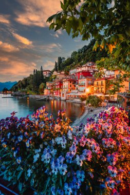 Varenna, İtalya - Mayıs 2021: Como Gölü üzerindeki Varenna köyü gün batımında aydınlık evlerle