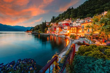 Varenna, İtalya - Mayıs 2021: Como Gölü üzerindeki Varenna köyü gün batımında aydınlık evlerle