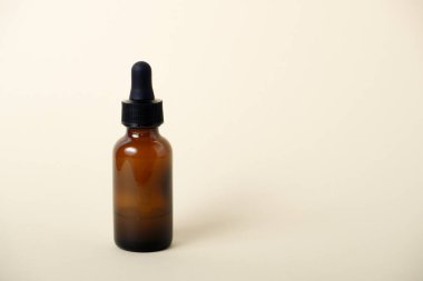 Kehribar damlası şişesinde serum yağı var. Bej arka planda pipeti olan serum cam şişe..