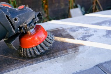 İnşaatçı bir açı öğütücüyle çalışıyor. Tel temizleme fırçası. Pas ve betondan yapılmış temizleme metali. İşçi, metalden pas temizlemek için öğütücü kullanıyor