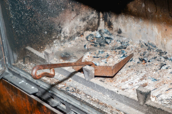 Fireplace cleaning. Fireplace cleaning tools. A shovel with ash in a burnt-out fireplace.