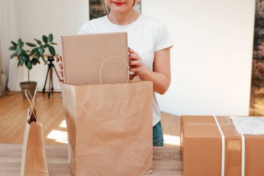 Ekolojik ambalaj. Sevimli, tanınmayan bir kadın hediyelerini çevre dostu geri dönüşümlü kağıt torbalara sarar..