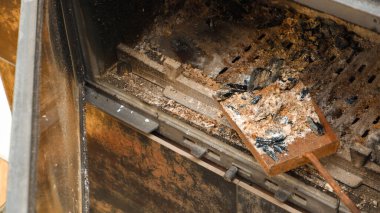 Şömine temizliği. Şömine temizleme aletleri. Yanmış bir şöminede kül dolu bir kürek..