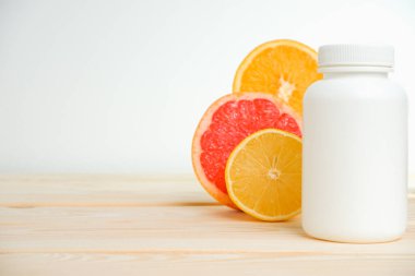 Vitaminler. Turunçgillerin arka planında vitamin için beyaz boş bir şişe. lemon. Turuncu. Boş ilaç şişesi.