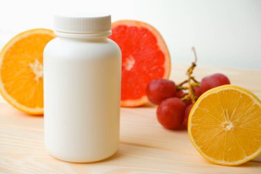 Vitaminler. Turunçgillerin arka planında vitamin için beyaz boş bir şişe. lemon. Turuncu. Boş ilaç şişesi.