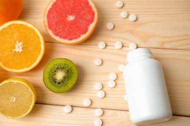 Vitaminler. Tıbbi konsept. Eczane ya da doğal. Vitaminli beyaz şişe, dağınık haplar. Sulu narenciye dilimleri. lemon. Turuncu. Greyfurt.