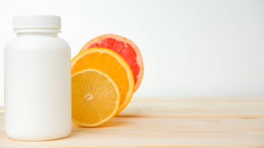 Vitaminler. Turunçgillerin arka planında vitamin için beyaz boş bir şişe. lemon. Turuncu. Boş ilaç şişesi.