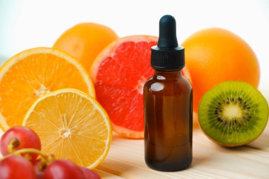 İçi narenciye yağı dolu bir şişe. Sulu olgun turunçgil dilimleri. lemon. Turuncu. Greyfurt. Üzüm. Cilt bakımı. Kozmetoloji.