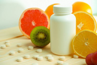 Vitaminler. Tıbbi konsept. Eczane ya da doğal. Vitaminli beyaz şişe, dağınık haplar. Sulu narenciye dilimleri. lemon. Turuncu. Greyfurt.