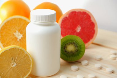 Vitaminler. Tıbbi konsept. Eczane ya da doğal. Vitaminli beyaz şişe, dağınık haplar. Sulu narenciye dilimleri. lemon. Turuncu. Greyfurt.