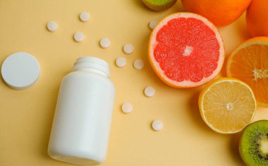 Vitaminler. Tıbbi konsept. Eczane ya da doğal. Vitaminli beyaz şişe, dağınık haplar. Sulu narenciye dilimleri. lemon. Turuncu. Greyfurt.
