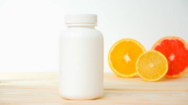 Vitaminler. Turunçgillerin arka planında vitamin için beyaz boş bir şişe. lemon. Turuncu. Boş ilaç şişesi.