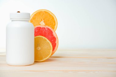 Vitaminler. Turunçgillerin arka planında vitamin için beyaz boş bir şişe. lemon. Turuncu. Boş ilaç şişesi.