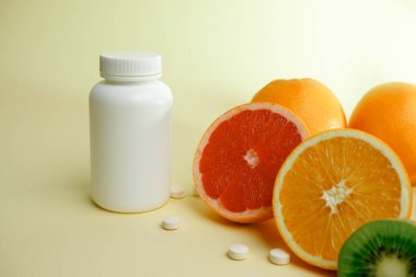 Vitaminler. Tıbbi konsept. Eczane ya da doğal. Vitaminli beyaz şişe, dağınık haplar. Sulu narenciye dilimleri. lemon. Turuncu. Greyfurt.