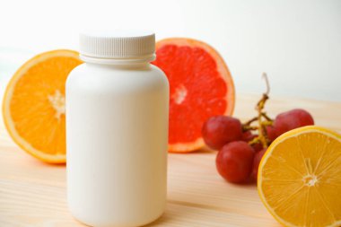 Vitaminler. Turunçgillerin arka planında vitamin için beyaz boş bir şişe. lemon. Turuncu. Boş ilaç şişesi.