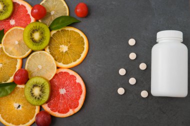 Vitaminler. Turunçgillerin arka planında vitamin için beyaz boş bir şişe. Gri taş arka plan. Boş ilaç şişesi.