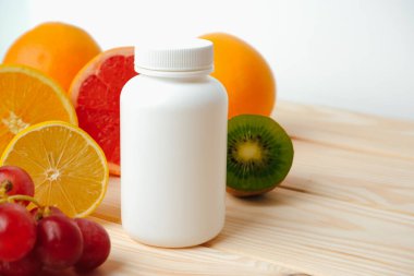 Hap mı vitamin mi? Ahşap bir masada vitamin için beyaz boş bir şişe. Sulu narenciye dilimleri. lemon. Turuncu. Greyfurt. Üzüm.