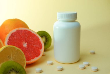 Vitaminler. Tıbbi konsept. Eczane ya da doğal. Vitaminli beyaz şişe, dağınık haplar. Sulu narenciye dilimleri. lemon. Turuncu. Greyfurt.