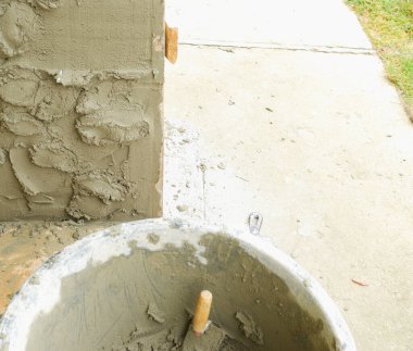 Konteynırdaki çimento alçısından. Bir duvarı alçılama işlemi.