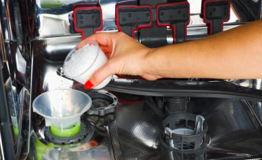 Bulaşık makinesine tuz ekliyorum. Bir kadının eli, suyu bulaşık makinesine yumuşatmak için tuz döküyor..