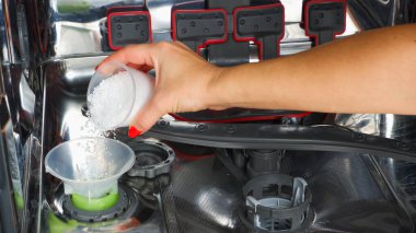 Bulaşık makinesine tuz ekliyorum. Bir kadının eli, suyu bulaşık makinesine yumuşatmak için tuz döküyor..