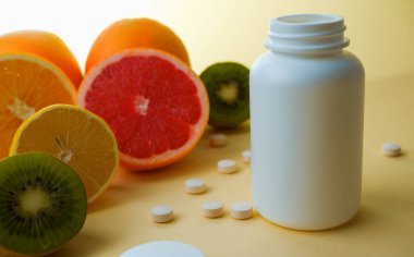Vitaminler. Tıbbi konsept. Eczane ya da doğal. Vitaminli beyaz şişe, dağınık haplar. Sulu narenciye dilimleri. lemon. Turuncu. Greyfurt.