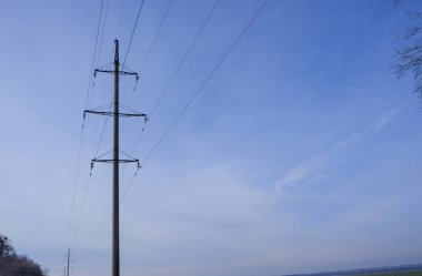 Yüksek voltajlı elektrik hattı. Kablolar ve direkler mavi gökyüzüne karşı. Elektrik endüstrisi.