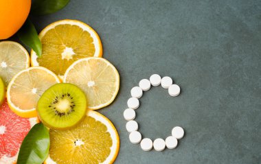 Vitamin konsepti. C vitamini tabletlerinin yanında taze sulu dilimlenmiş narenciye meyveleri. Sağlıklı ekolojik gıda ve takviyeler arasında seçim yapın..