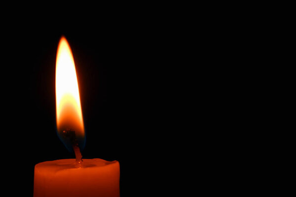 Single lit candle with quite flame. Dramatic burning candle flame on a black background with copy space