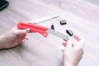 Bir kadın montaj bıçağının bıçağını değiştirir. Elleri yakın çekim. Eller bıçağı ve yeni keskin bıçağı tutsun. Seçici odak.