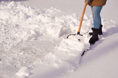 Kışın karları temizler. Bir kadın bölgedeki karları kürekle temizliyor..