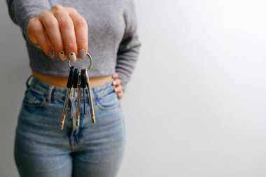 Kot pantolonlu ve bluzlu çekici bir kadın elinde bir sürü anahtar tutuyor. İnsanların yaşam tarzı konsepti. kopyalama alanı. Ev anahtarlarını tut, işaret parmağını bir kenara koy.