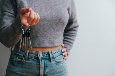 Kot pantolonlu ve bluzlu çekici bir kadın elinde bir sürü anahtar tutuyor. İnsanların yaşam tarzı konsepti. kopyalama alanı. Ev anahtarlarını tut, işaret parmağını bir kenara koy.