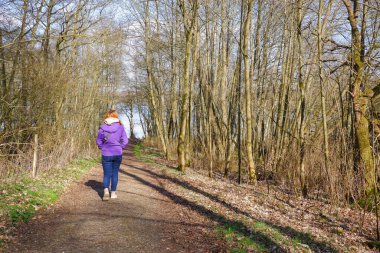 Bir kadın ormanda bir patika boyunca yürür. Arkadan bak. - Evet. Yürüyüş. Hareket, spor, sağlıklı yaşam tarzı.