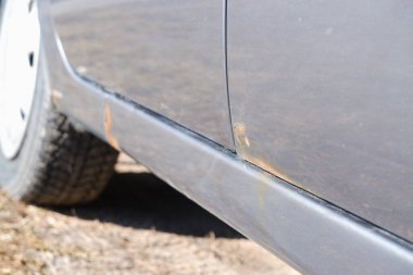 Paslı ve metal aşınmalı bir araba kapısı. Kaput arabasındaki paslı lekeyi yok et. Gümüş arabanın gövdesinde ve kapılarında sert aşınma ve pas var..