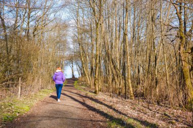 Bir kadın ormanda bir patika boyunca yürür. Arkadan bak. - Evet. Yürüyüş. Hareket, spor, sağlıklı yaşam tarzı.