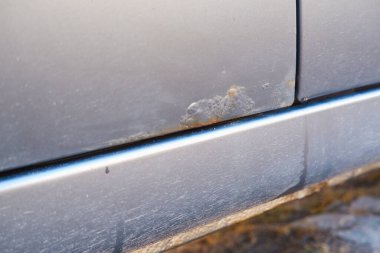 Pas ve ele yakın çekim, seçici odaklanma. Bir adam arabanın kapısında kış reaksiyonlarının paslandığını gösterir..